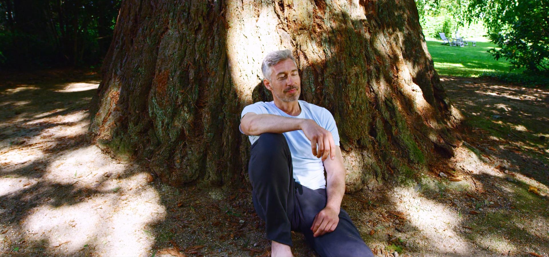 Ein Mann enspannt draußen an einem Baum
